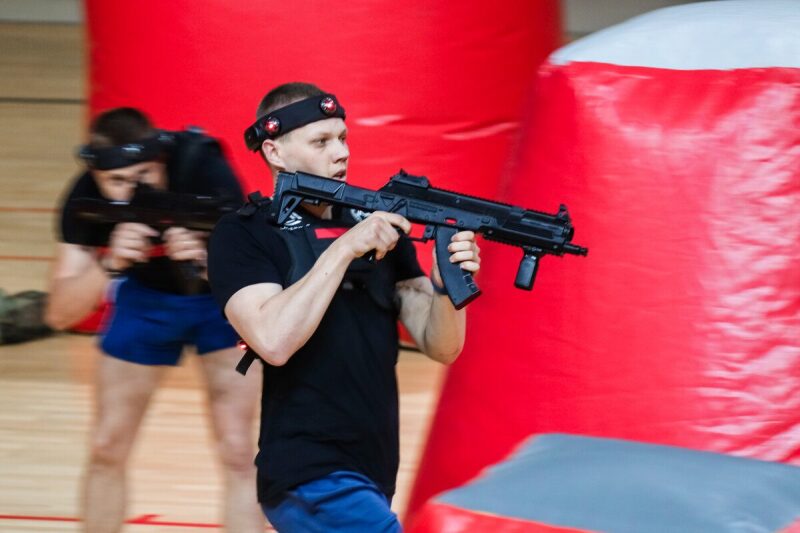 Игрок LASERWAR с автоматом занял позицию у красного препятствия.